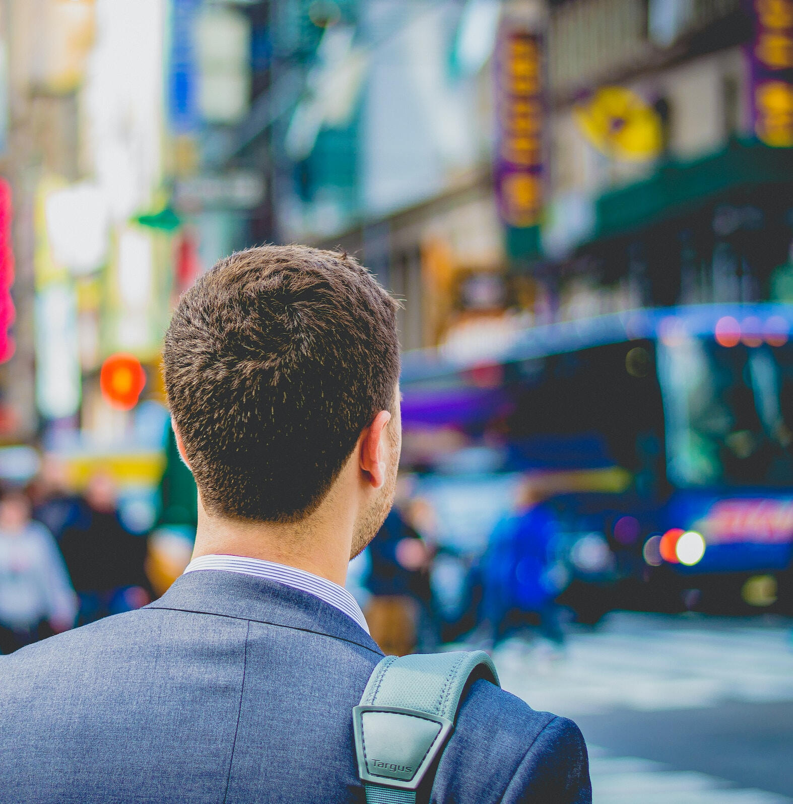 person with brown hair and blue suit looks on at city